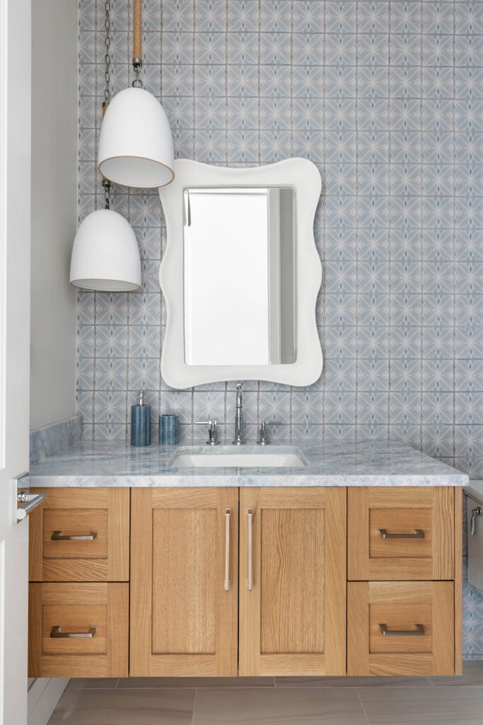 A coastal bathroom with a scalloped mirror by Trinity Custom Homes on St. Armands, Sarasota, Florida